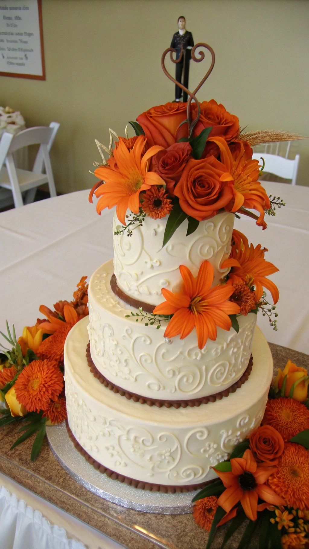 25 Stunning Burnt Orange Wedding Ideas for Your Dream Day A three-tier wedding cake decorated with orange flowers and a couple figurine on top.