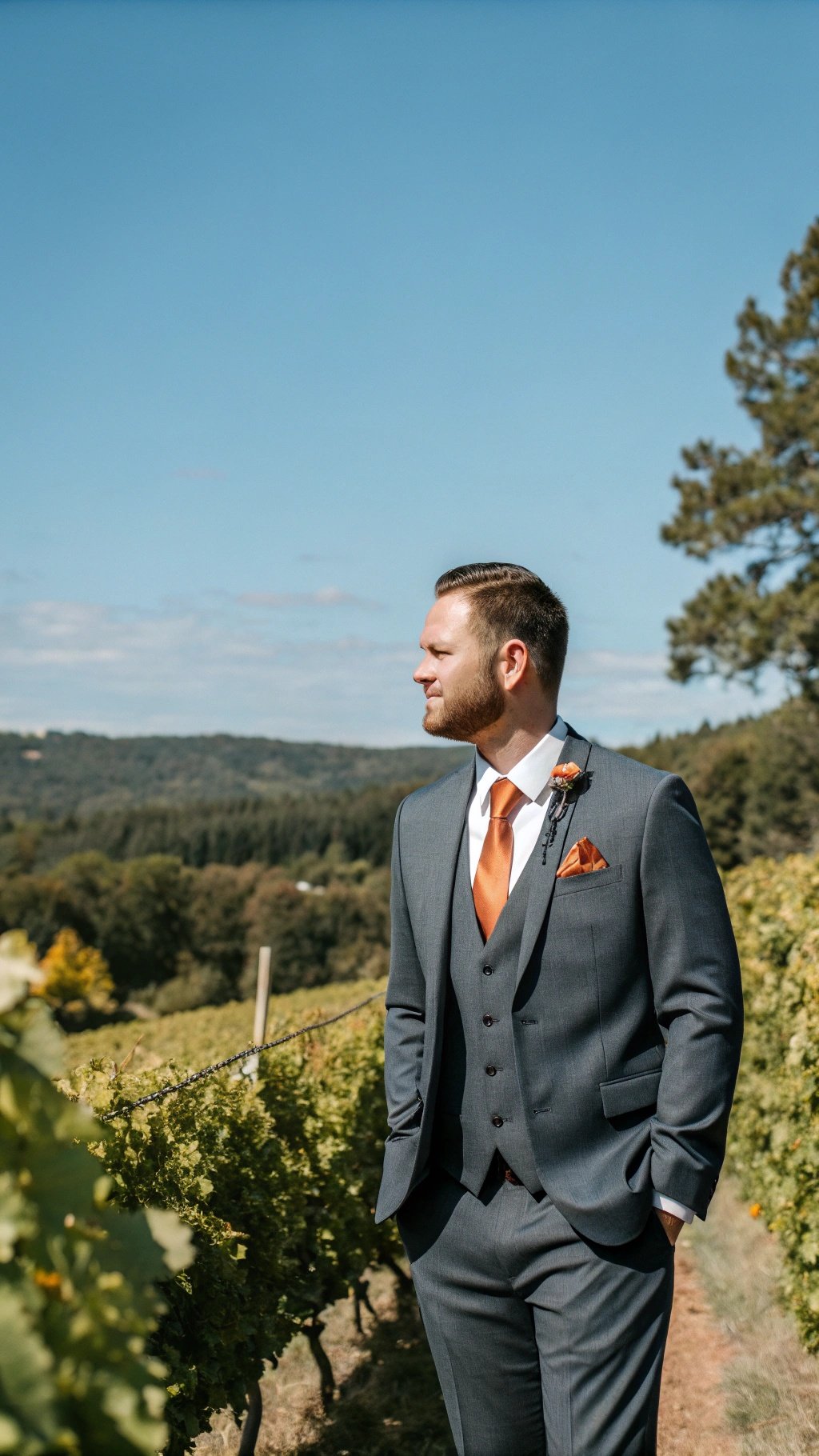 25 Stunning Burnt Orange Wedding Ideas for Your Dream Day Groom in a gray suit with burnt orange accents standing in a vineyard